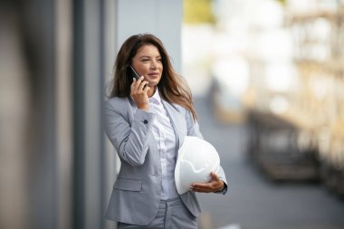 Gülümseyen kadın telefonda konuşuyor ve kaskını tutuyor.