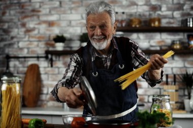 Mutlu son sınıf öğrencisi elinde spagetti ve gülümsüyor.