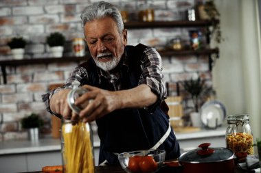 Son sınıf öğrencisi mutfakta kavanozdan makarna alıyor.