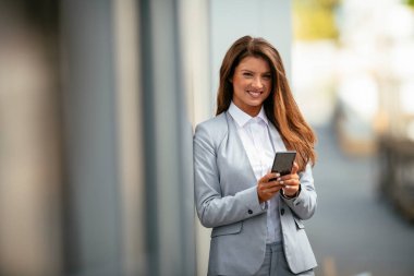 Akıllı telefon tutan ve kameraya gülümseyen bir kadın.