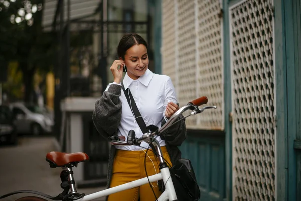 Gülümseyen Genç Bir Kadın Bisikletin Yanında Dururken Kulaklık Takıyor — Stok fotoğraf