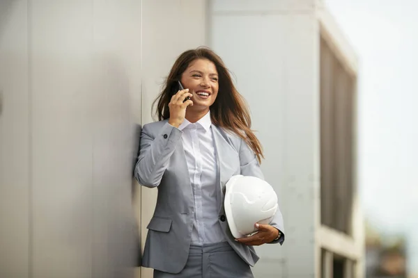 Χαμογελαστή Γυναίκα Μιλώντας Στο Τηλέφωνο Και Κρατώντας Κράνος — Φωτογραφία Αρχείου