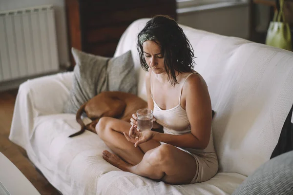 Mujer Sosteniendo Píldora Vaso Agua Con Perro Sofá — Foto de Stock