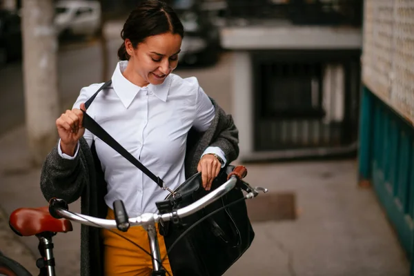 Gülümseyen Genç Kadın Bisikletin Yanında Duran Çantaya Bakıyor — Stok fotoğraf