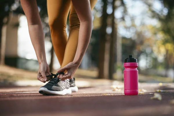 Potret Wanita Mengikat Tali Sepatu Pelatih Dengan Botol Air Tanah — Stok Foto