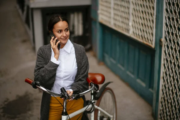 Bisikletin Yanında Dururken Telefonla Konuşan Gülümseyen Genç Kadın — Stok fotoğraf
