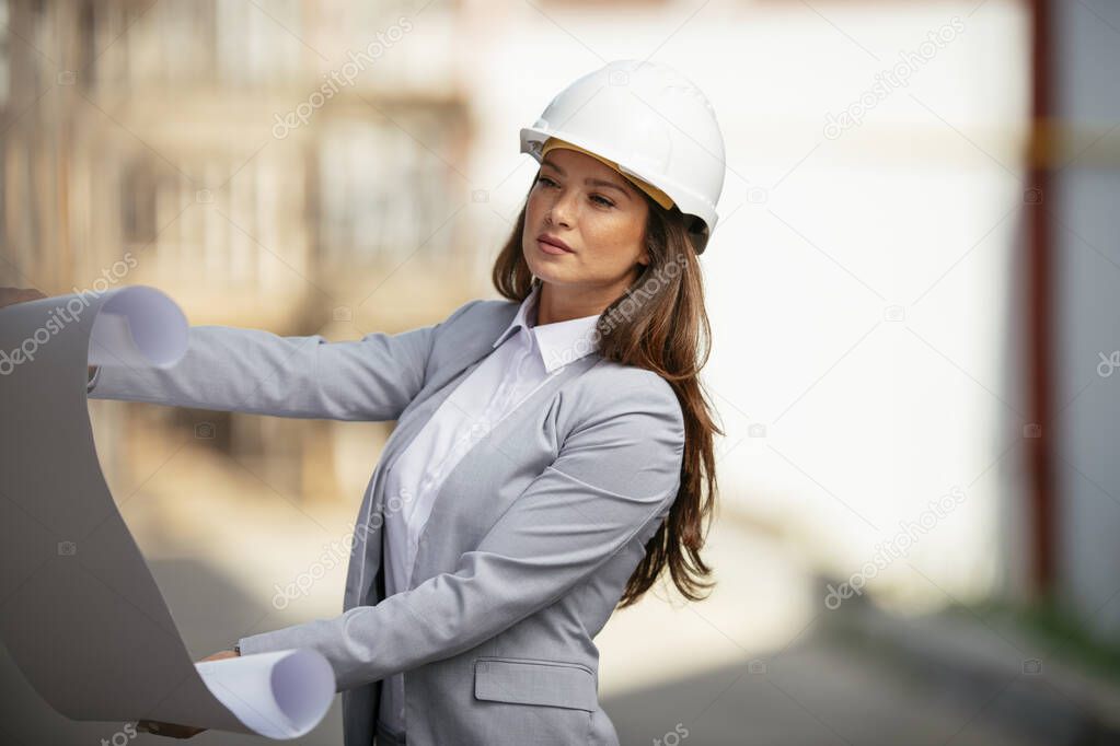 young woman architect in formal wear holding paper plan