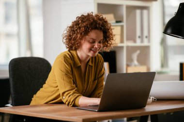 Ofiste dizüstü bilgisayarda çalışan bir kadın.