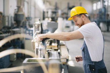 Üretim hattındaki fabrika işçisi. Fabrikada çalışan kasklı bir adam..