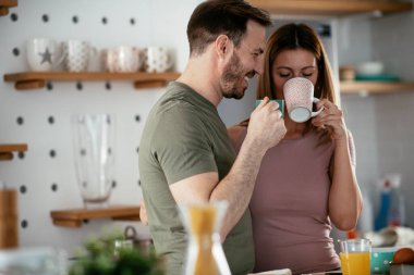 Sevgili çift kahvaltı hazırlarken kahve içiyorlar..