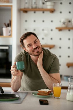 Adam mutfakta kahvaltı yapıyor.