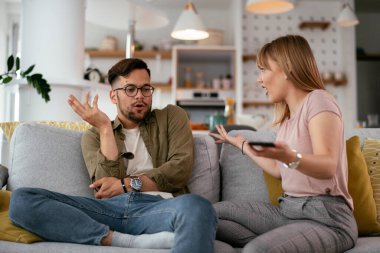 Karı koca kanepede tartışıyor. Kızgın eş kocasına bağırıyor.