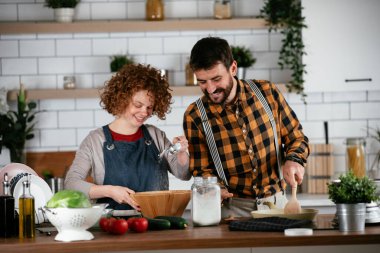 Erkek arkadaş ve kız arkadaş evde lezzetli yemekler yapıyor. Aşkın çifti mutfakta yemek pişiriyor.