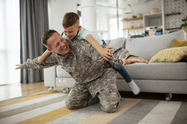 Askerler evlerinde oğluyla oynuyorlar. 