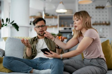 Karı koca kanepede tartışıyor. Kızgın eş kocasına bağırıyor.