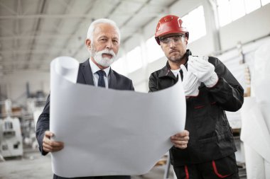 Mimar ve işçi proje üzerinde çalışıyor. Fabrikada çalışan meslektaşlar.