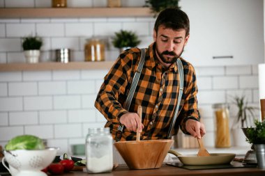 Mutfaktaki yakışıklı adamın portresi. Genç adam lezzetli yemekler hazırlıyor..