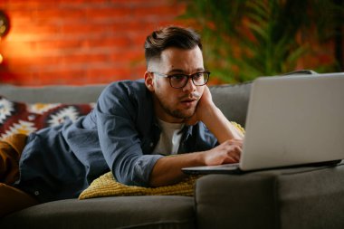 Evdeki dizüstü bilgisayarda dizi izleyen bir adam..