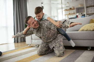 Askerler evlerinde oğluyla oynuyorlar. 