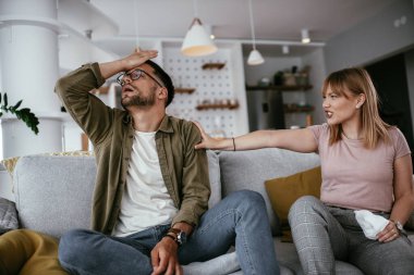 Erkek arkadaşı ve kız arkadaşı kanepede tartışıyor. Kızgın kadın erkek arkadaşına bağırıyor..