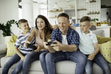 Anne ve baba evde çocuklarla video oyunu oynarken eğleniyorlar..