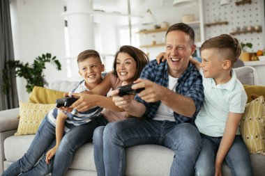 Anne ve baba evde çocuklarla video oyunu oynarken eğleniyorlar..