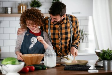 Erkek arkadaş ve kız arkadaş evde lezzetli yemekler yapıyor. Aşkın çifti mutfakta yemek pişiriyor.