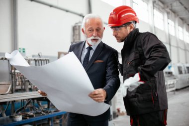 Mimar ve işçi proje üzerinde çalışıyor. Fabrikada çalışan meslektaşlar.