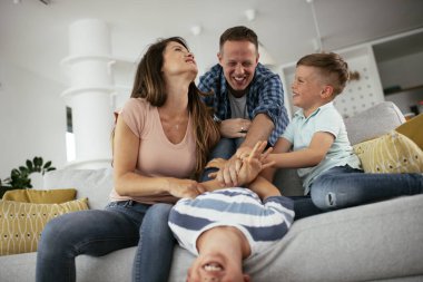 Mutlu aile kanepede birlikte vakit geçiriyor. 