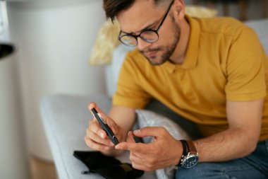 Diyabetli adam evde tükenmez kalemle kan örneği alıyor..