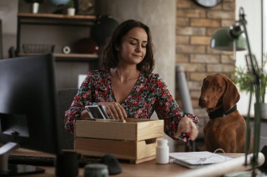Ofisteki genç iş kadını belgeleri düzenliyor. Ofiste köpeğiyle çalışan genç bir kadın.