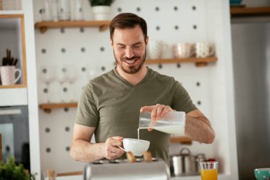 Adam mutfakta kahvaltı yapıyor.