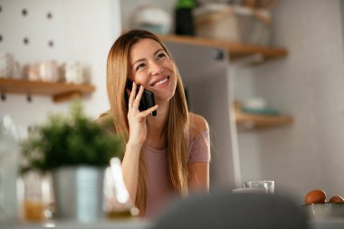 Mutfaktaki kadın. Mutfakta telefon kullanan güzel bir kadın..