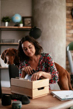 Ofisteki genç iş kadını belgeleri düzenliyor. Ofiste köpeğiyle çalışan genç bir kadın.