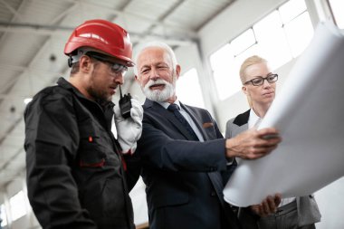 Mimarlar ve işçiler yeni projeyi planlarıyla tartışıyorlar. Fabrikada çalışan meslektaşlar..