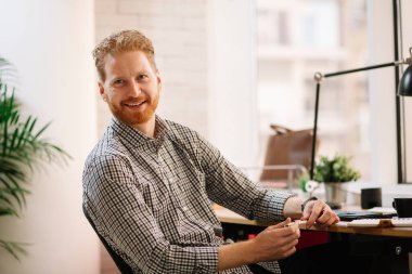 Genç kızıl iş adamı ofiste notlar alıyor.