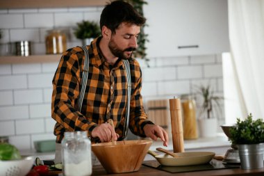 Mutfaktaki yakışıklı adamın portresi. Genç adam lezzetli yemekler hazırlıyor..