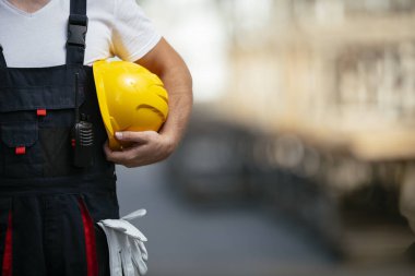 Sarı miğferi elinde tutan fabrika işçisi