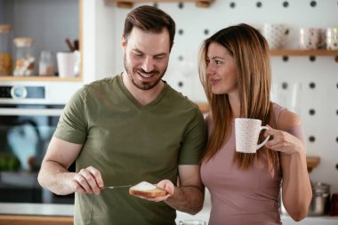 Genç çift evde sandviç yapıyor. Sevgi dolu çift mutfakta eğleniyor..
