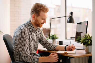 Ofiste çalışan bir iş adamı. Kızıl adam işyerinde oturuyor..