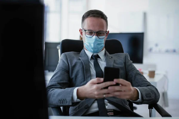 Handsome businessman with medical mask. Young businessman working in office.