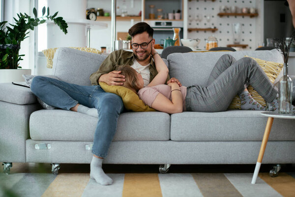 Young loving couple enjoying on sofa. Happy couple relaxing in living room..
