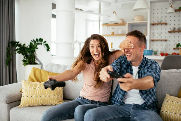 夫と妻は自宅でビデオゲームをプレイしながら楽しみを持っています — ストック写真
