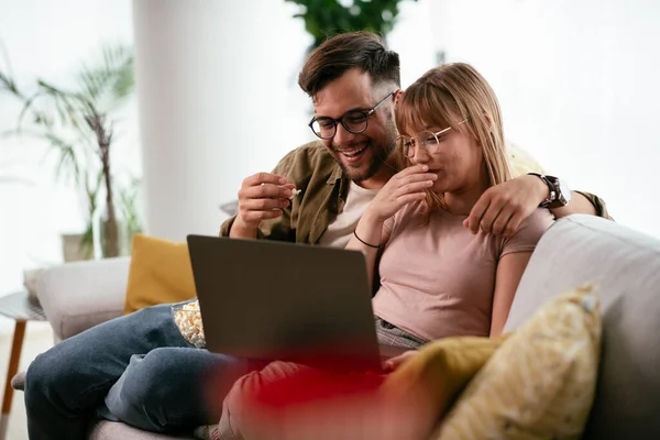 Young couple watching movie on laptop. Loving couple enjoying at home.