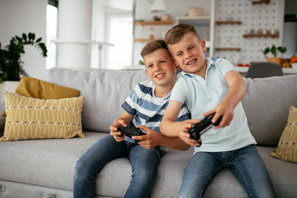 Young brothers having fun while playing video games in living room