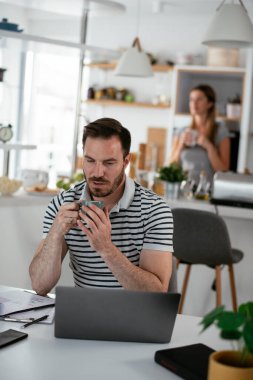Evde çalışan yorgun bir adam. Genç adam dizüstü bilgisayar kullanıyor.