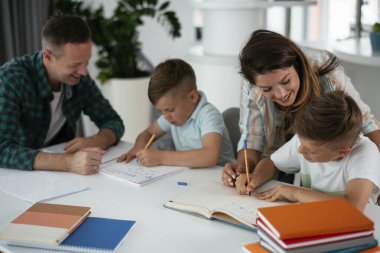 Anne ve baba oğullarına ev ödevlerinde yardım ederler.
