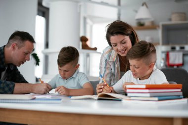 Anne ve baba oğullarına ev ödevlerinde yardım ederler.