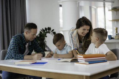 Anne ve baba oğullarına ev ödevlerinde yardım ederler.