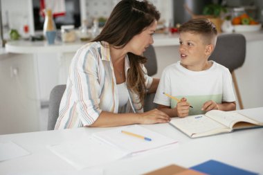 Güzel, genç bir anne çocuğuna ödevlerinde yardım ediyor..